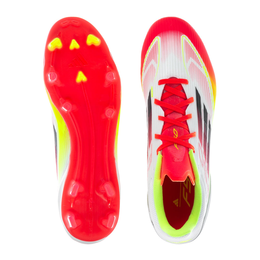 Side view of Adidas F50 League Low FGxMG soccer cleats on a grassy field, highlighting their lightweight design.
