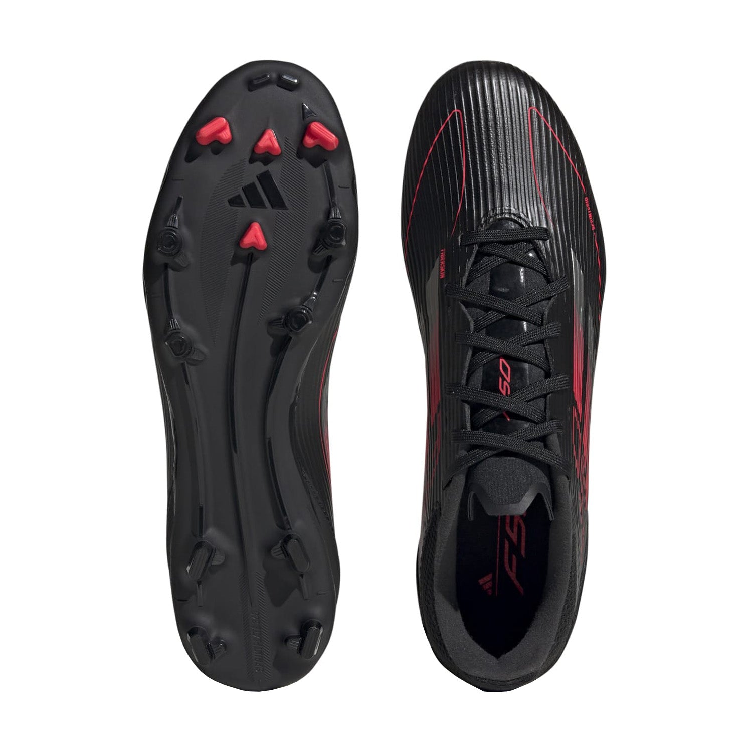 Overhead shot of adidas F50 League Low FGxMG cleats showing hybrid stud layout on dry grass