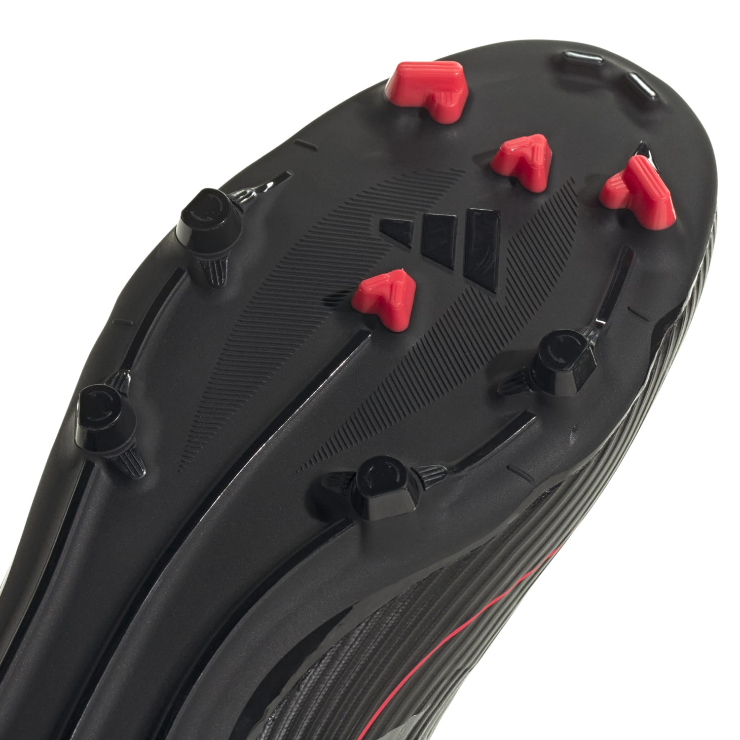 Overhead shot of adidas F50 League Low FGxMG cleats showing hybrid stud layout on dry grass