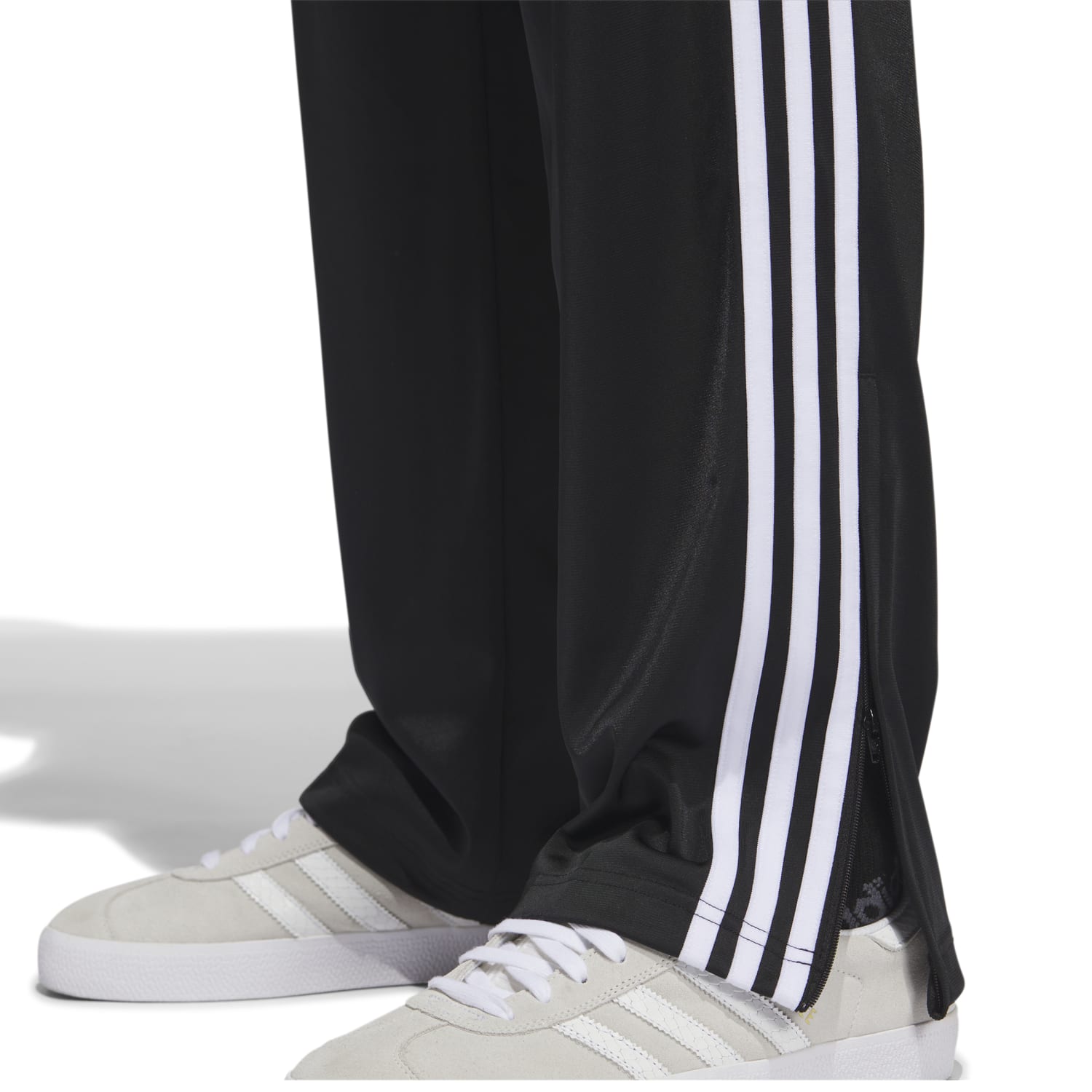 Side angle of runner tying shoes while wearing the best mens track pants for running—note the relaxed fit and trefoil logo