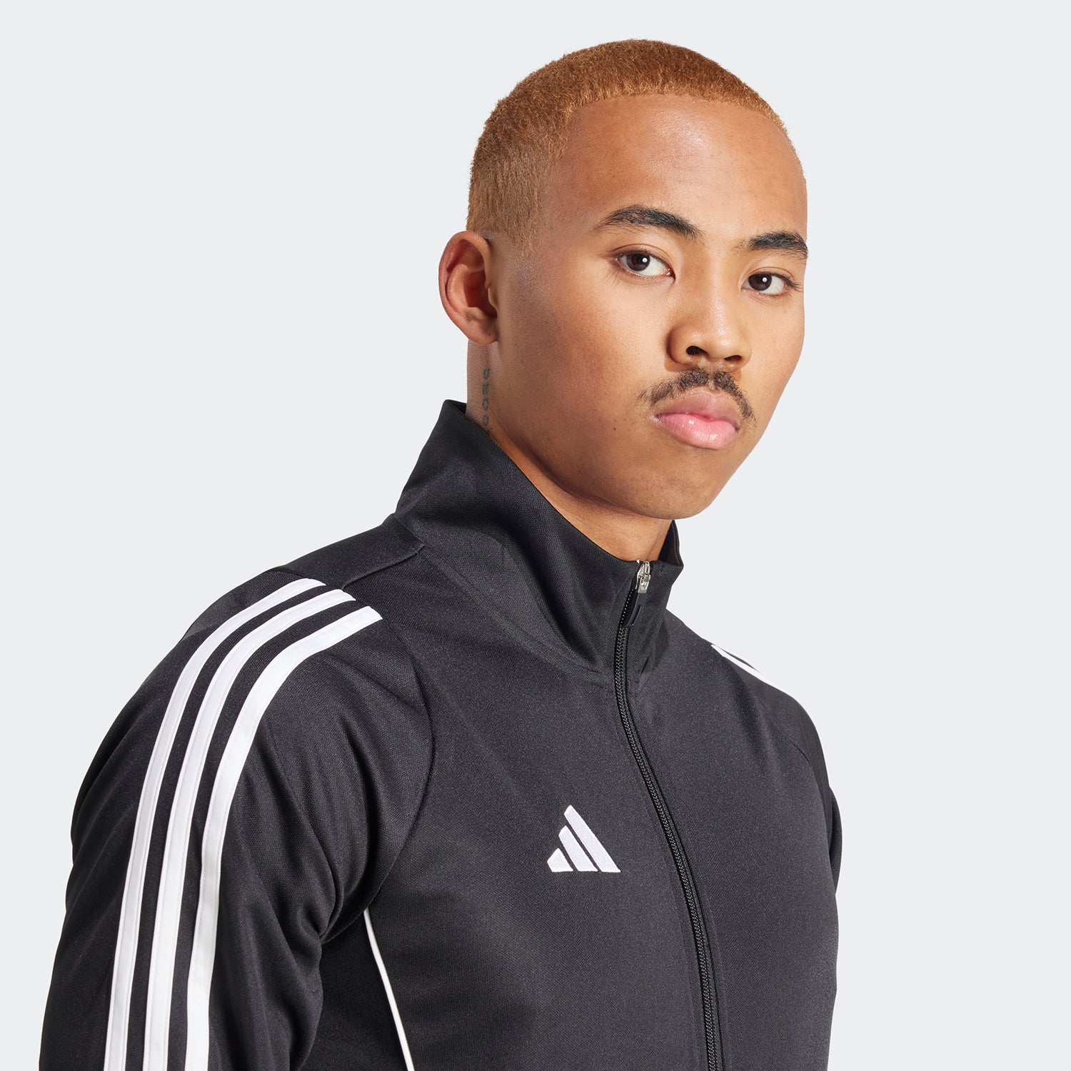 Side angle of runner wearing Tiro24 track jacket while jogging on foggy morning trail