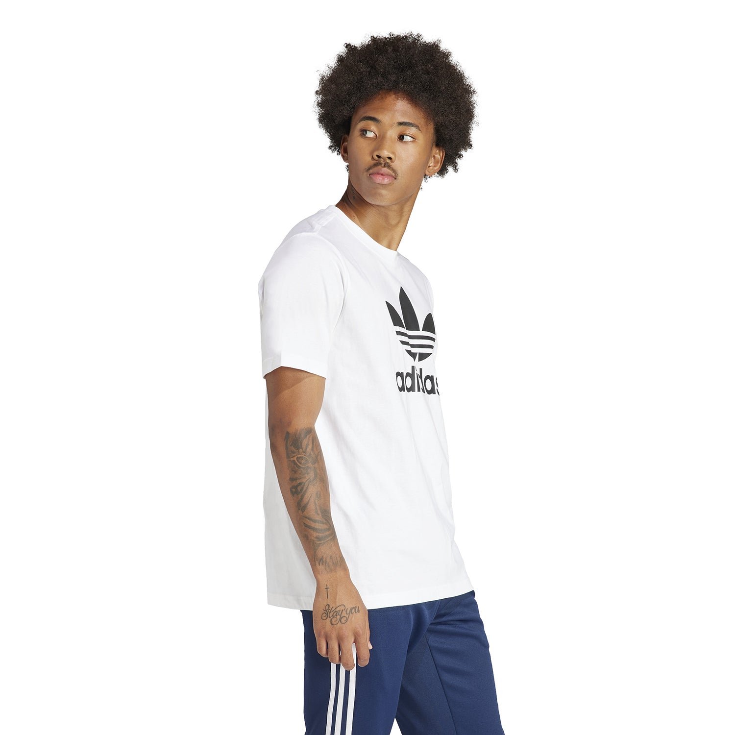 Lifestyle shot of a man wearing the Adidas Trefoil tee, paired with shorts and a jacket for a casual look.