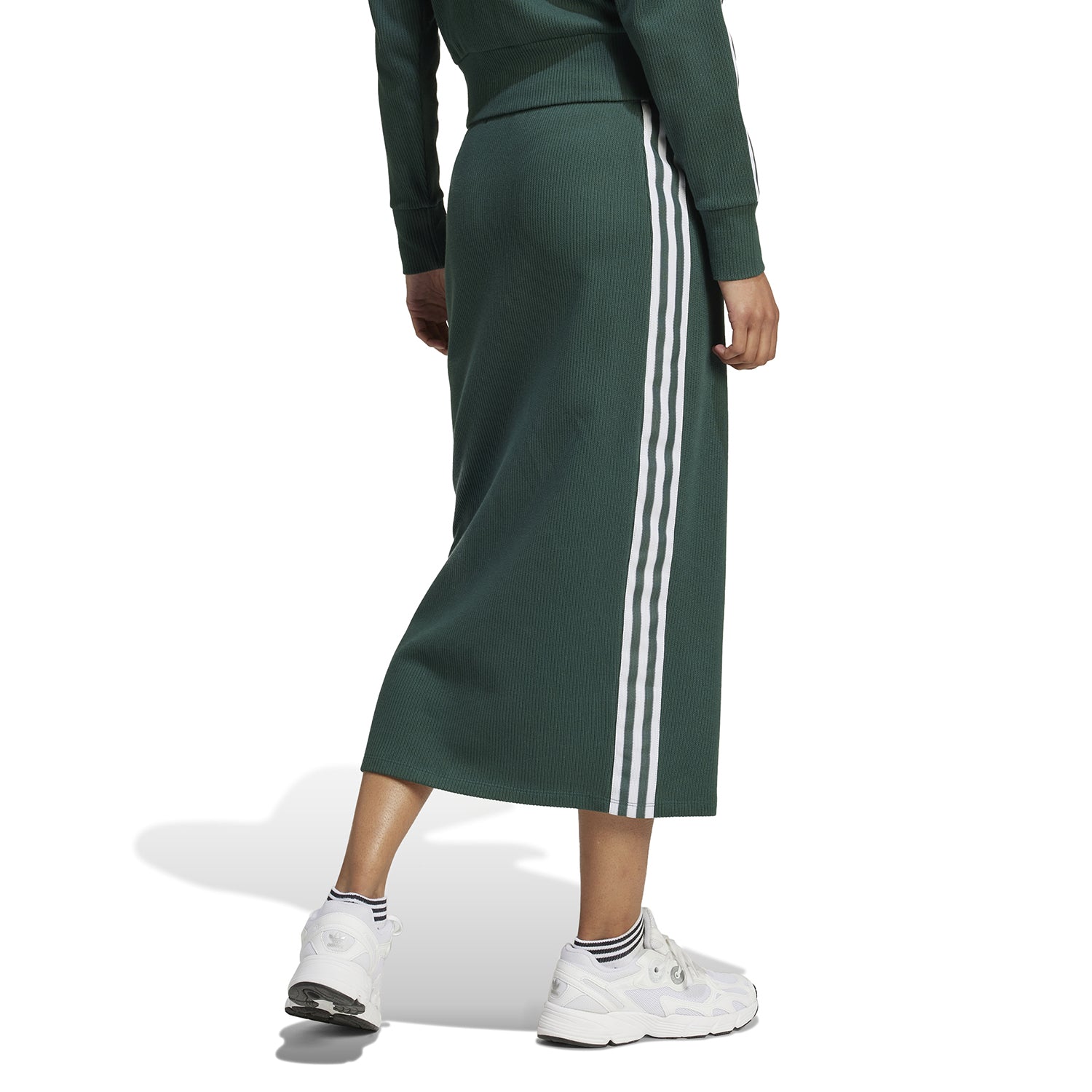 Back view showing the sleek silhouette of the recycled-cotton knitted skirt with three stripes
