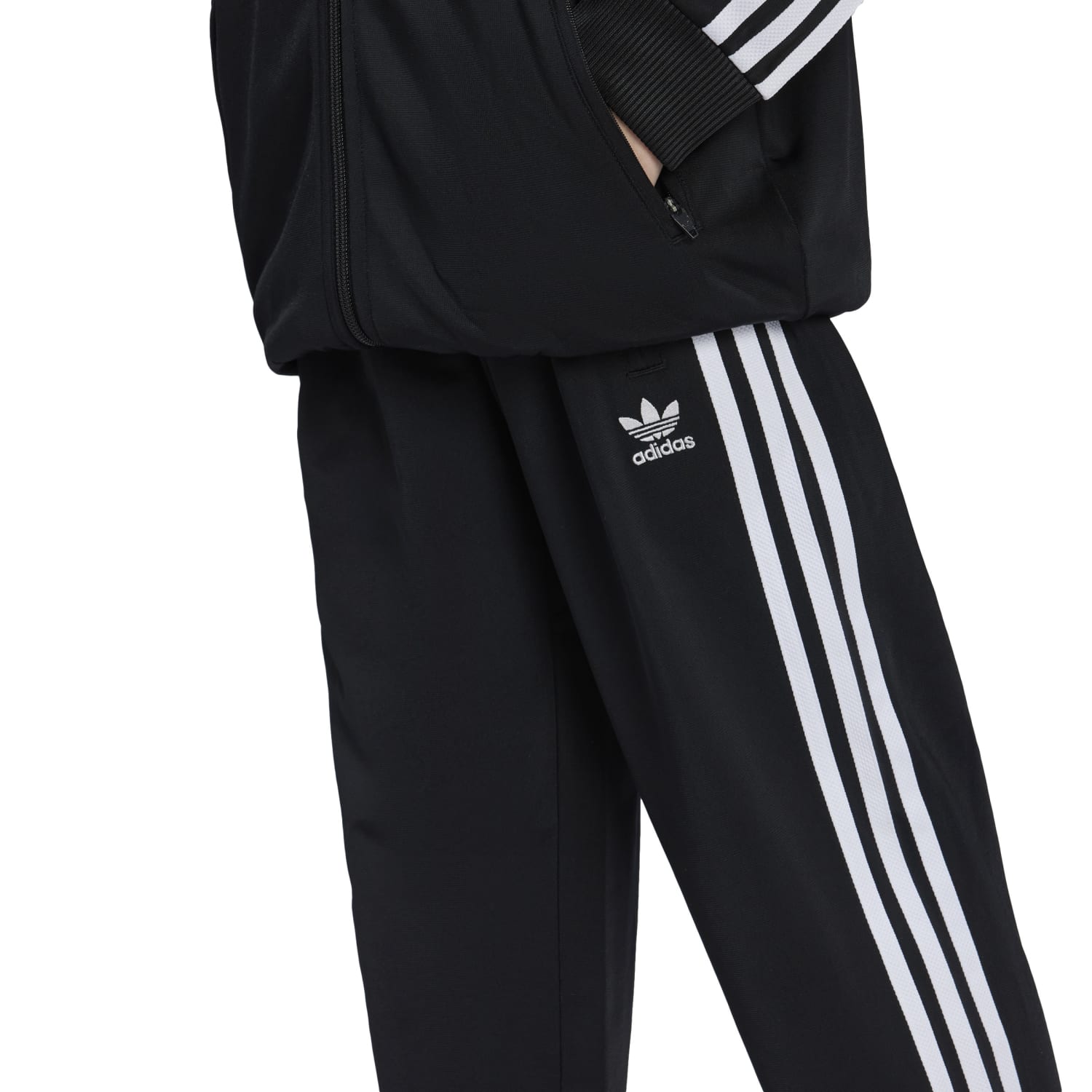Kids wearing adidas Firebird track pants during outdoor activity, showing the stripes and fit