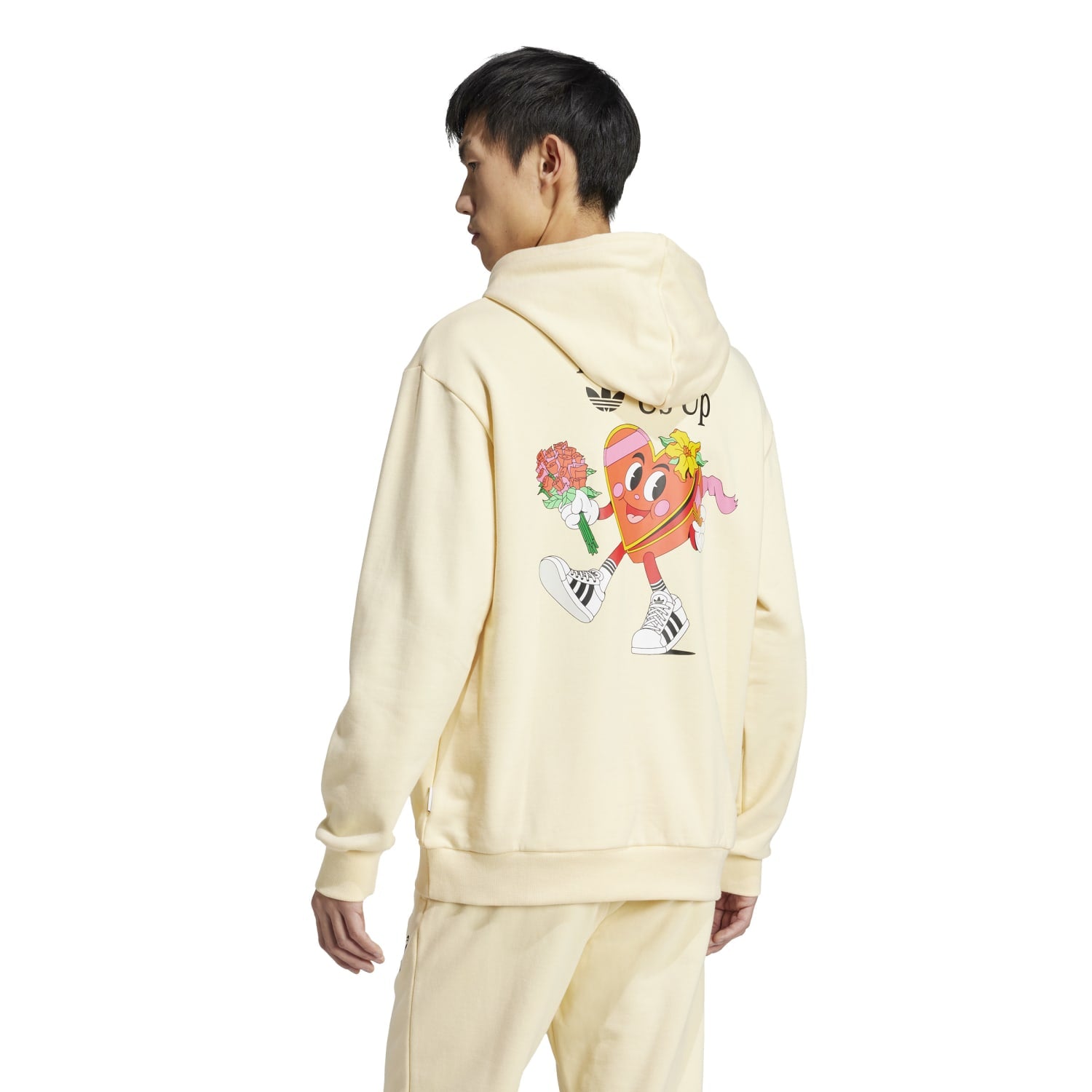 Side-angle lifestyle photo: guy walking dog wearing the warm adidas pullover during golden hour