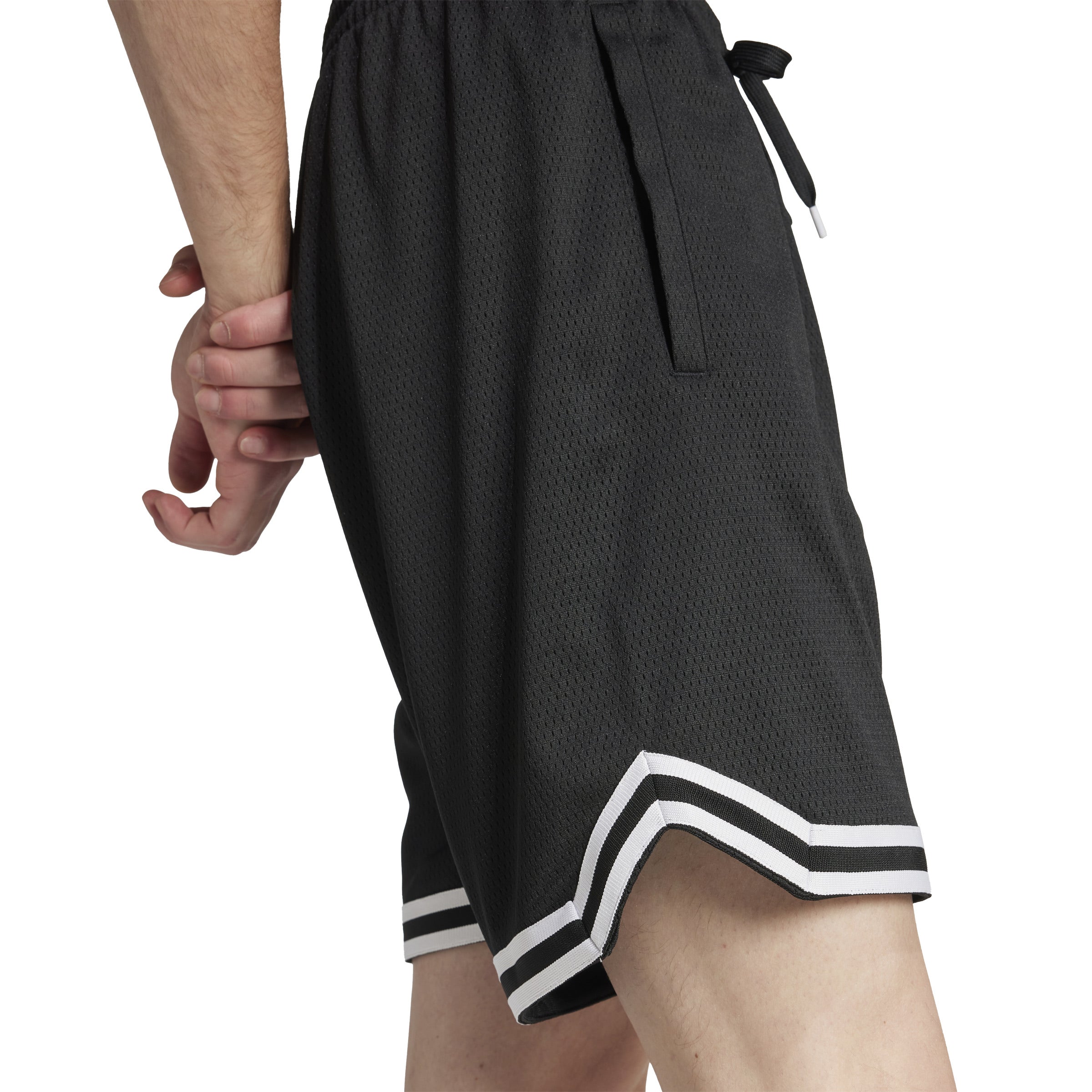 Male athlete in varsity sportswear performing a jump shot in basketball shorts