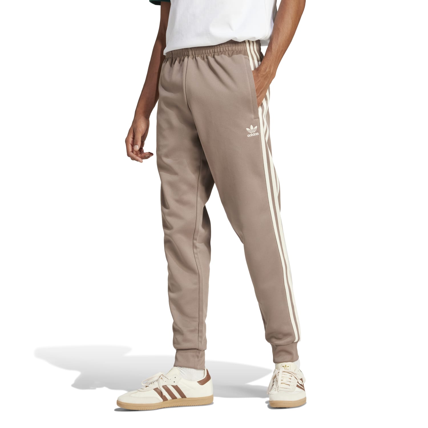 Man wearing Adidas Superstar Slim Fit Track Pants while jogging in a park, demonstrating their comfort and fit.