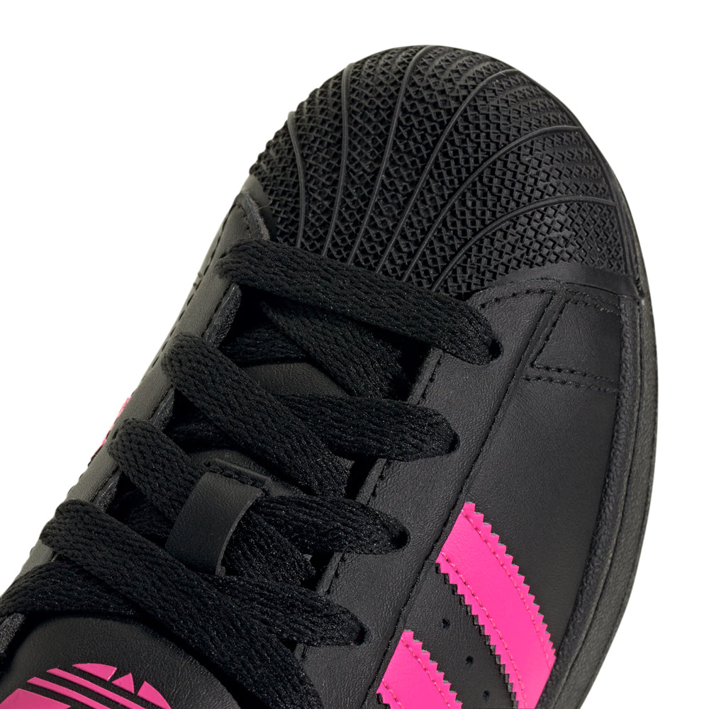Adidas Superstar Youth Sneakers on a playground, demonstrating durability and grip.
