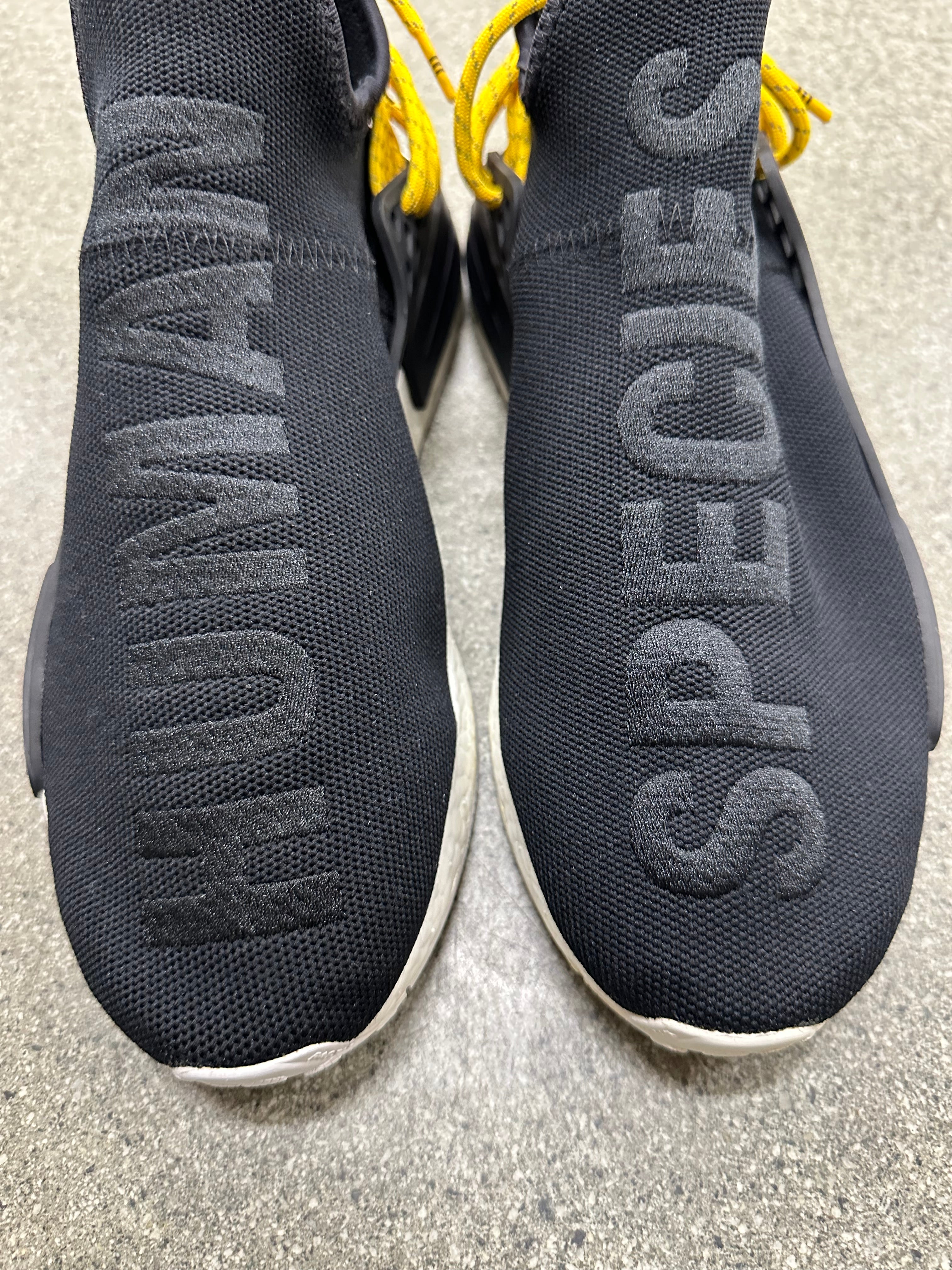 Lifestyle shot of woman wearing adidas human race NMD black sneakers during a casual walk