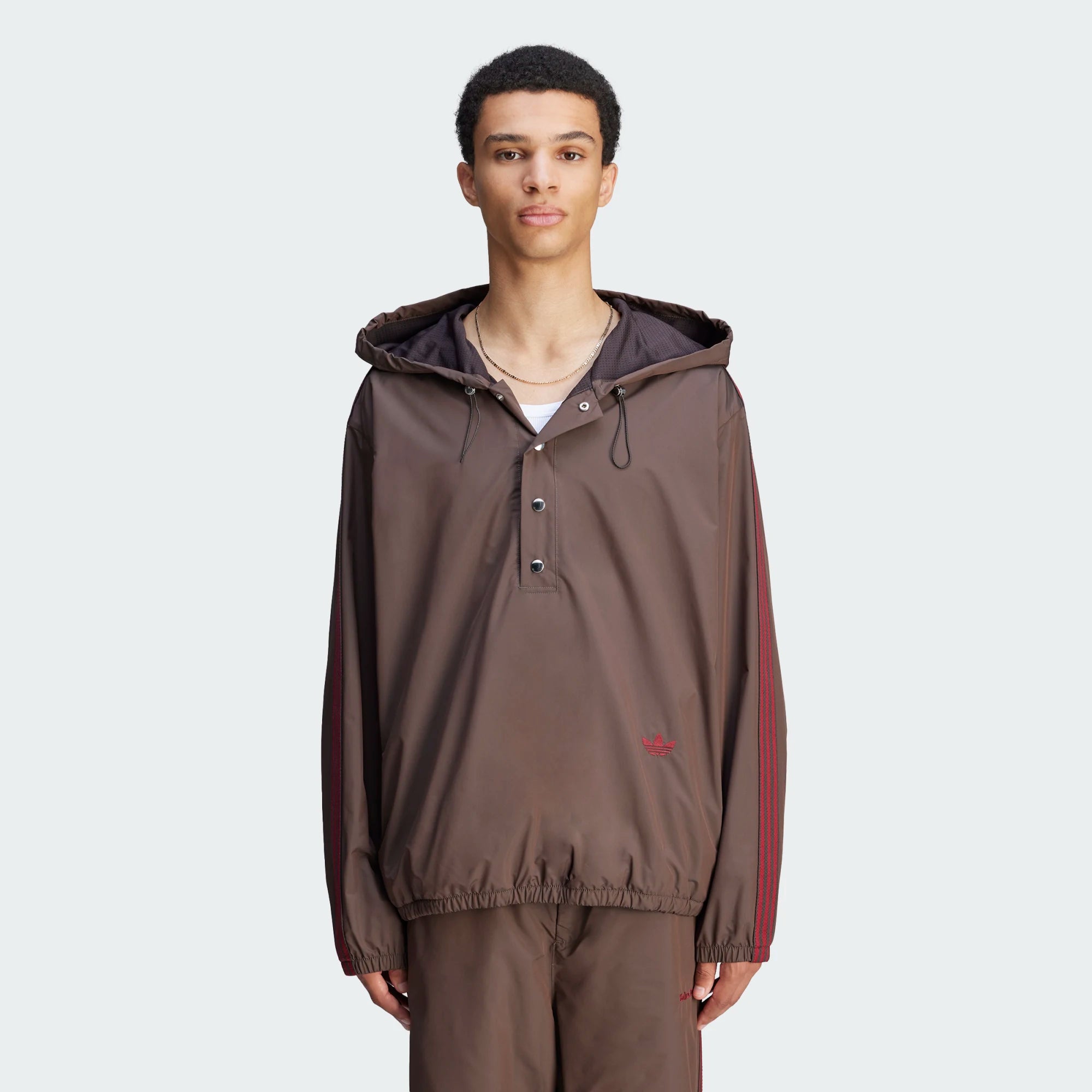 Side profile of model wearing the anorak in urban setting, hood cinched against light rain
