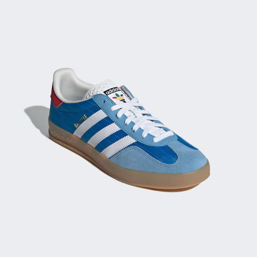 Detailed view of the Adidas Gazelle Indoor bright blue sneakers, highlighting the textured tongue and gum rubber sole.