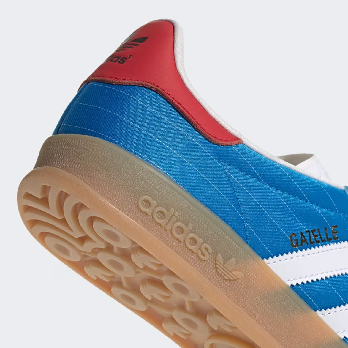 Detailed view of the Adidas Gazelle Indoor bright blue sneakers, highlighting the textured tongue and gum rubber sole.