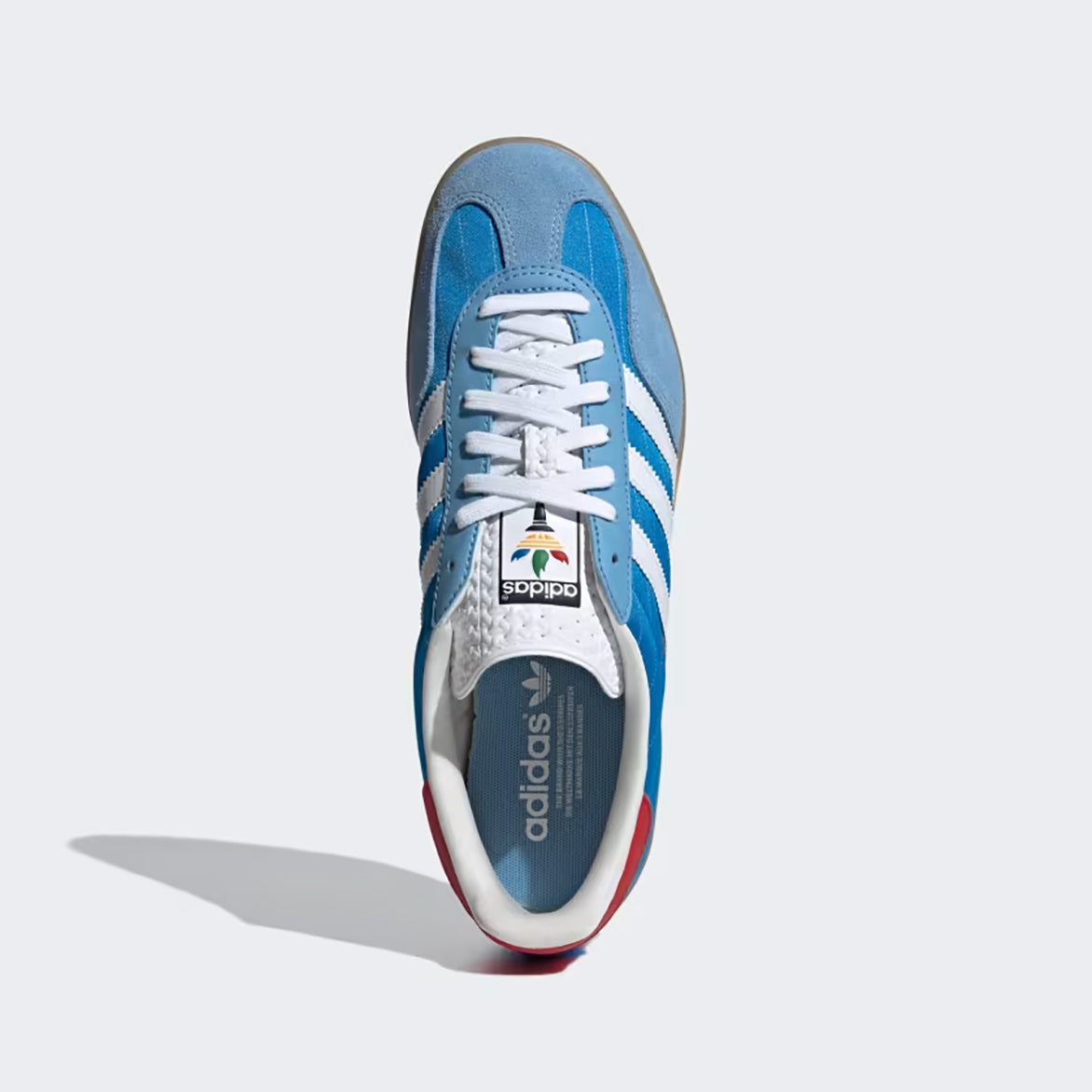 Close-up shot of the Adidas Gazelle Indoor bright blue sneakers showcasing the red leather heel and Trefoil logo on the tongue.