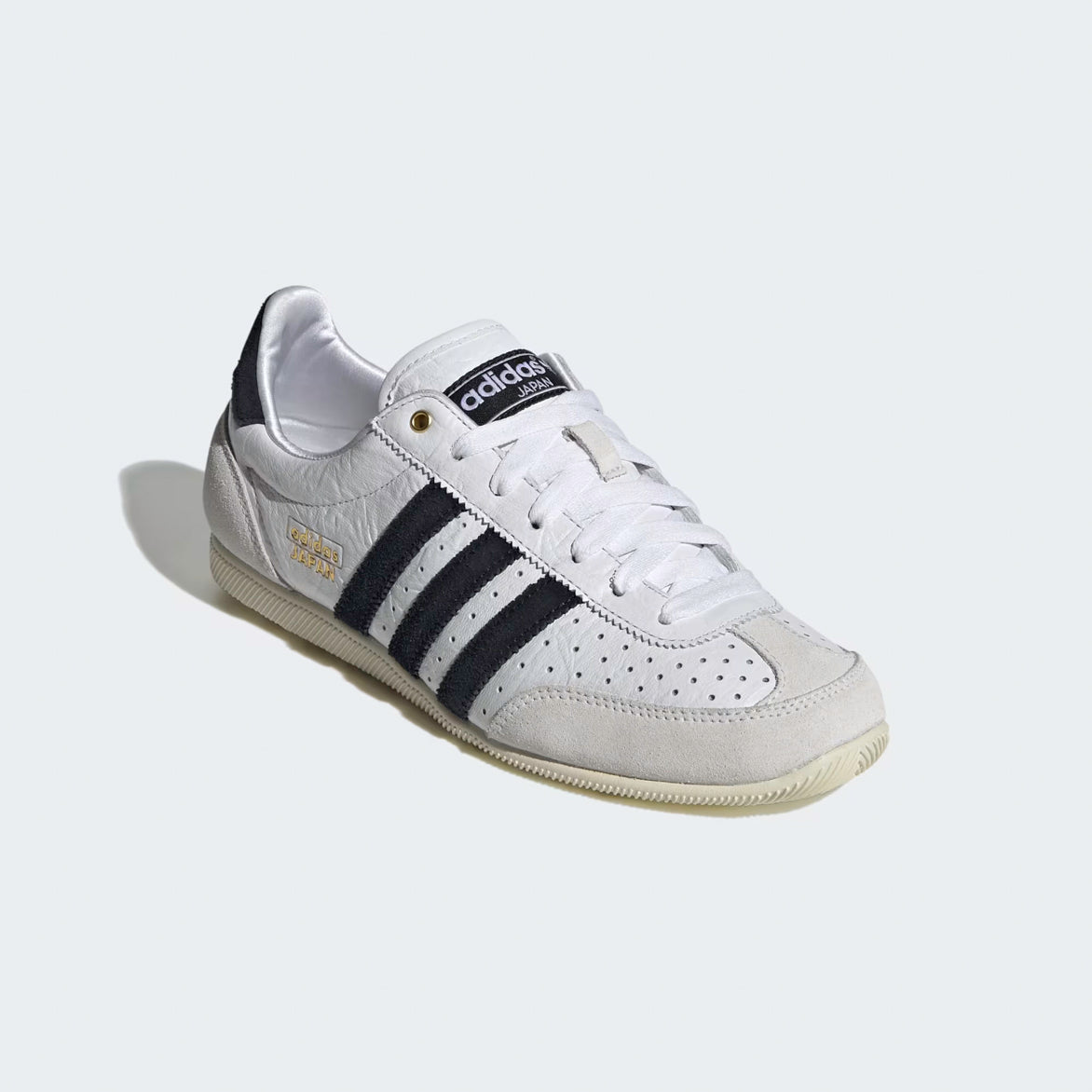 Close-up of the metallic gold eyelets and black suede stripes on womens Adidas shoes