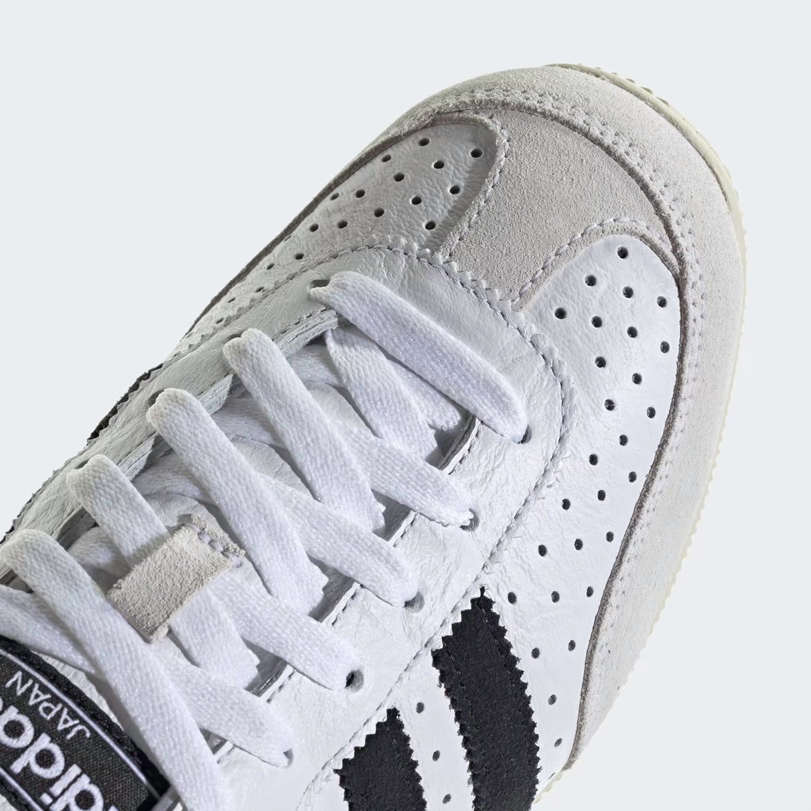 Adidas Japan limited edition sneakers with white leather upper and gold accents, side view