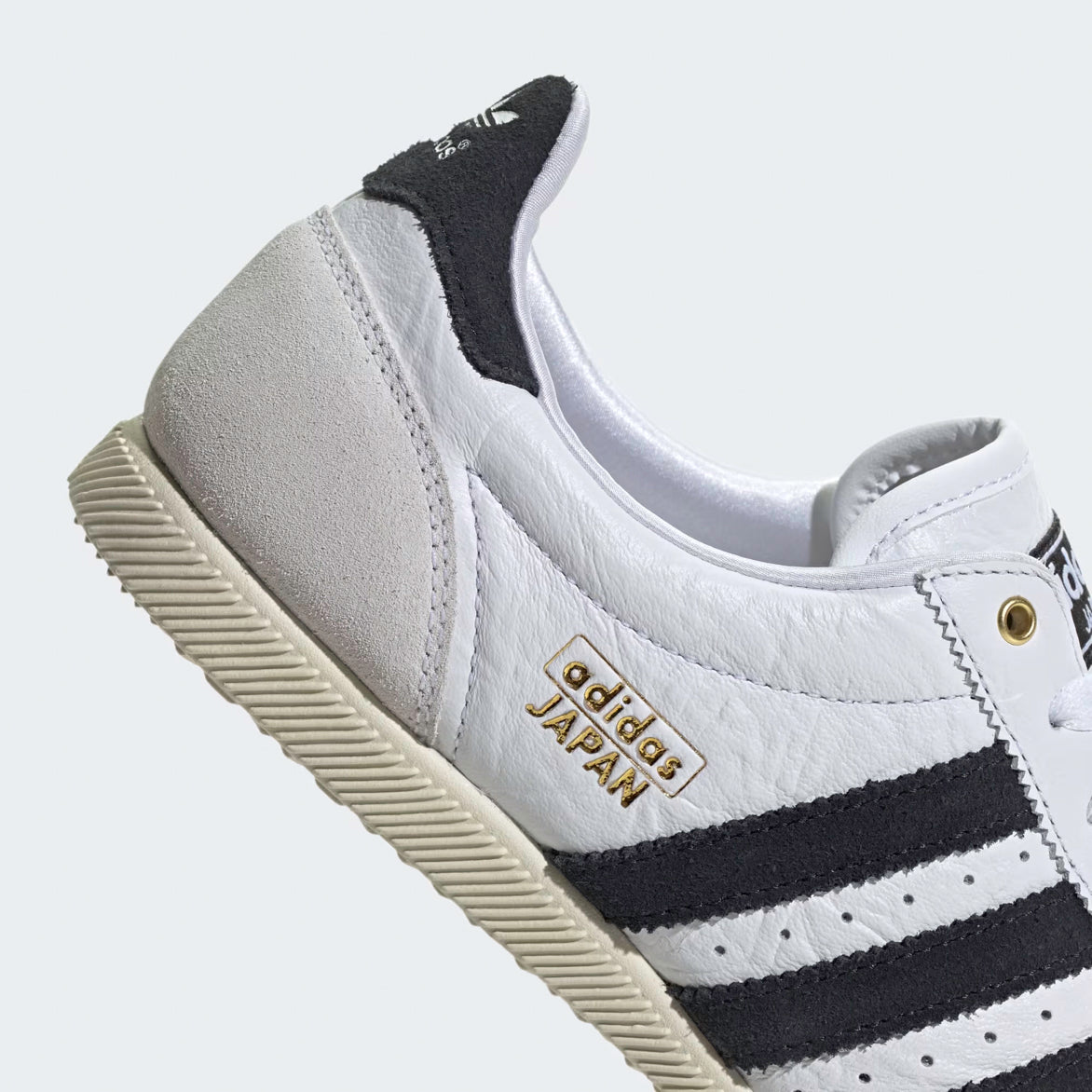 Close-up of the metallic gold eyelets and black suede stripes on womens Adidas shoes