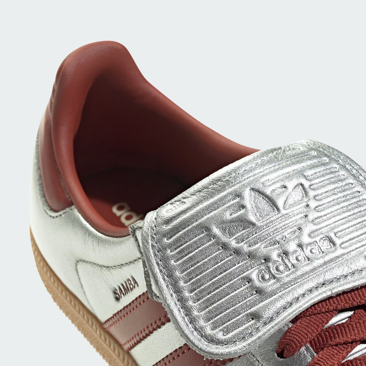 Close-up of Samba Long Tongue womens silver sneakers showcasing the embossed adidas logo and metallic finish.