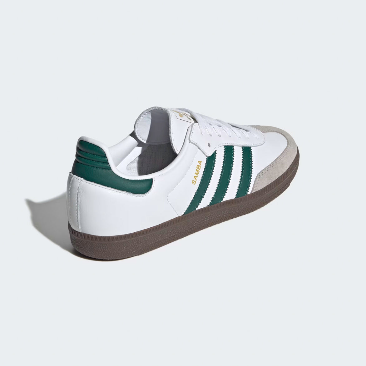 Top-down flat lay of limited edition Adidas Samba shoes with matching white laces, gold tongue tag, and green heel tab