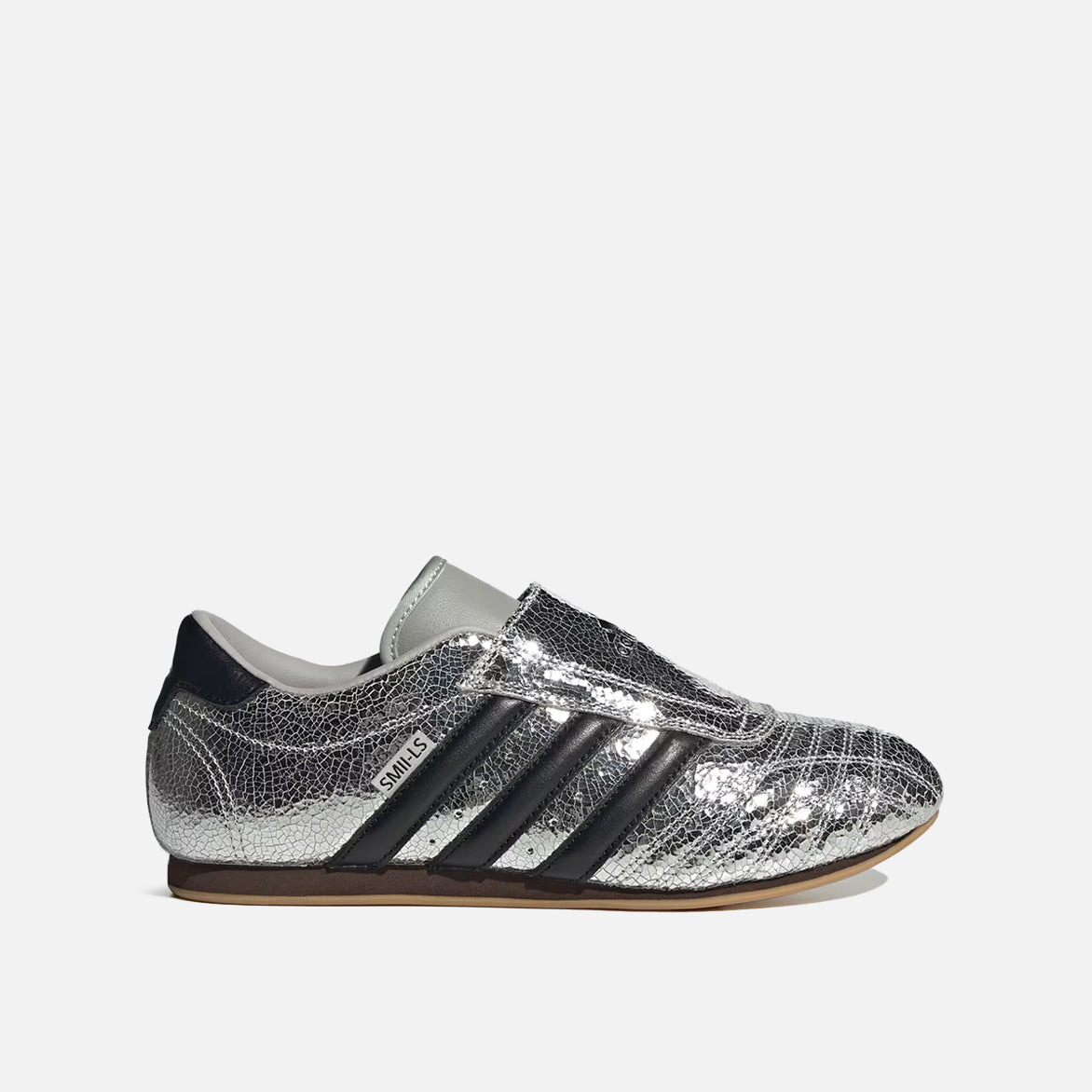 Close-up of silver metallic slip-on sneakers showing cracked leather texture and Trefoil logo