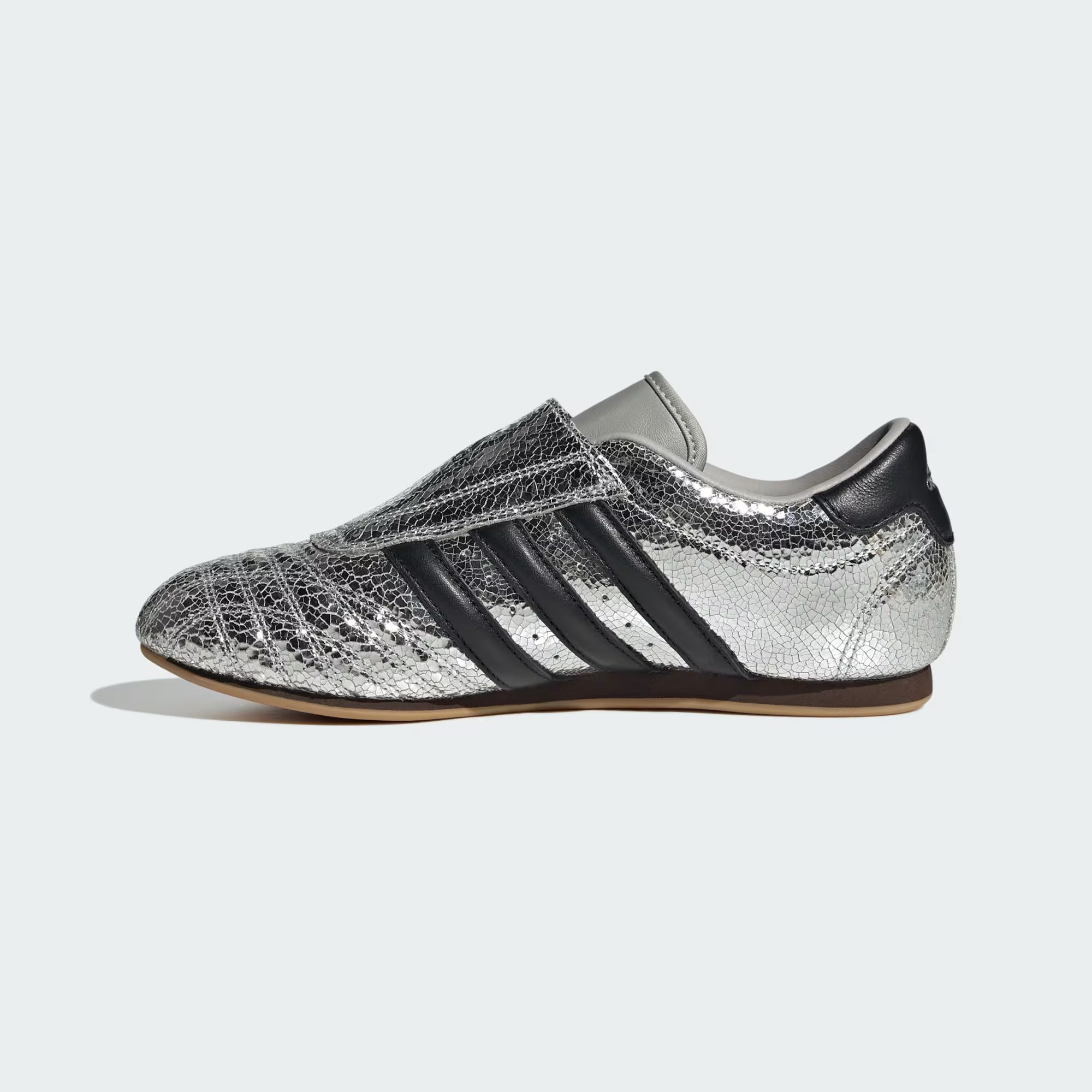 Styled image of silver metallic sneakers with black leather accents on a city street