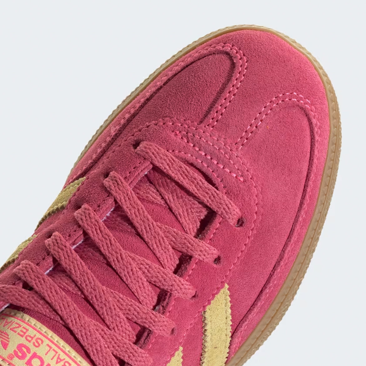 Close-up of dark-gum outsole and metallic silver heel tab highlighting suede texture
