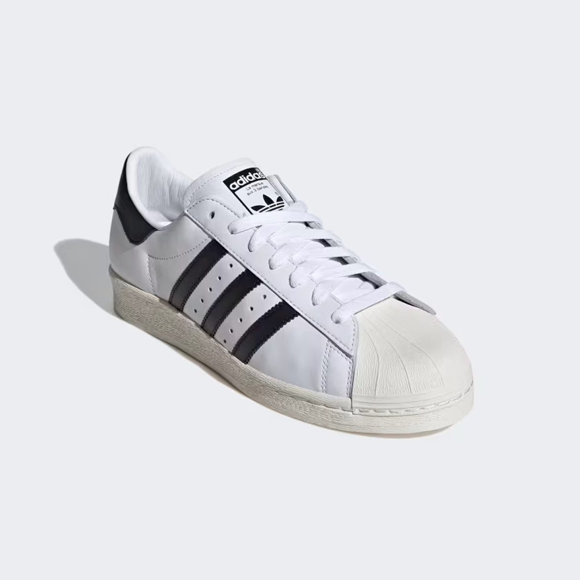 Close-up of the iconic rubber shell toe on the Adidas Superstar 82 sneakers.