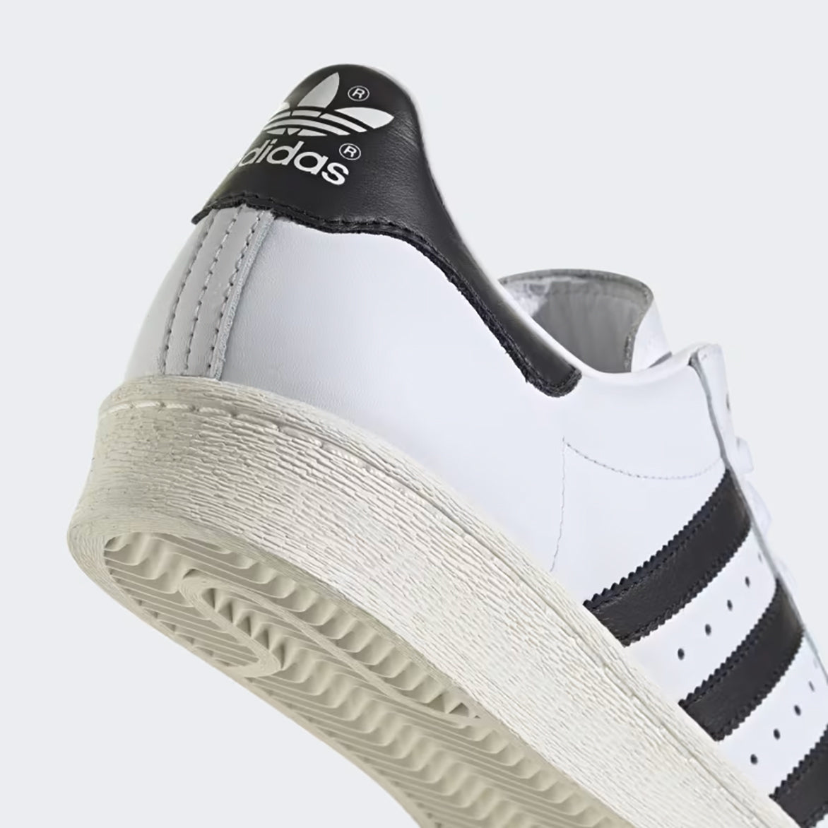 Close-up of the iconic rubber shell toe on the Adidas Superstar 82 sneakers.