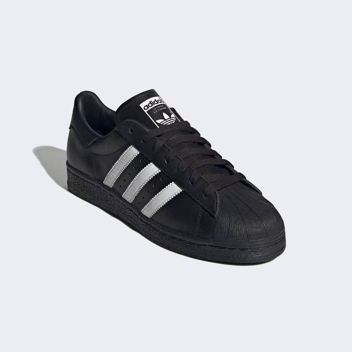 Close-up of rubber shell toe and trefoil logo on sneaker