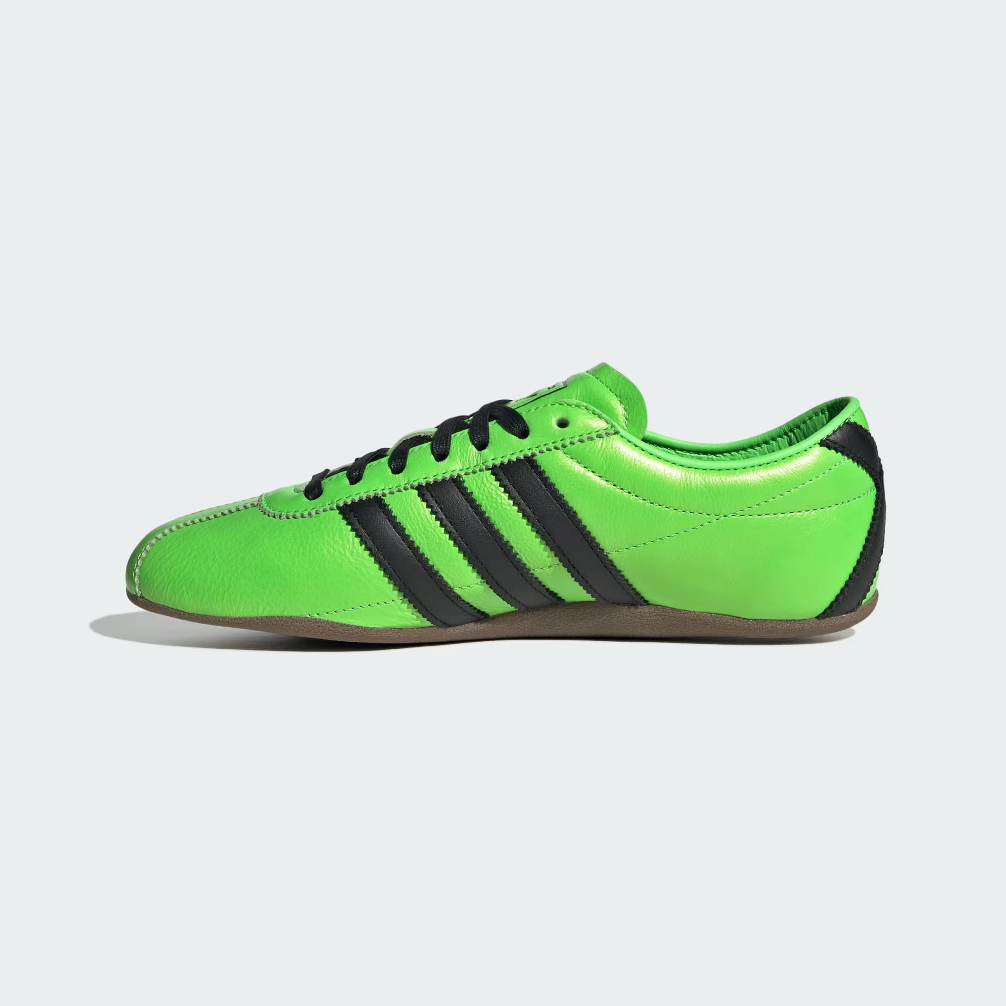 Lifestyle shot of a woman wearing Adidas Womens Limited Edition Tokyo Sneakers in Solar Green, perfect for casual outings.