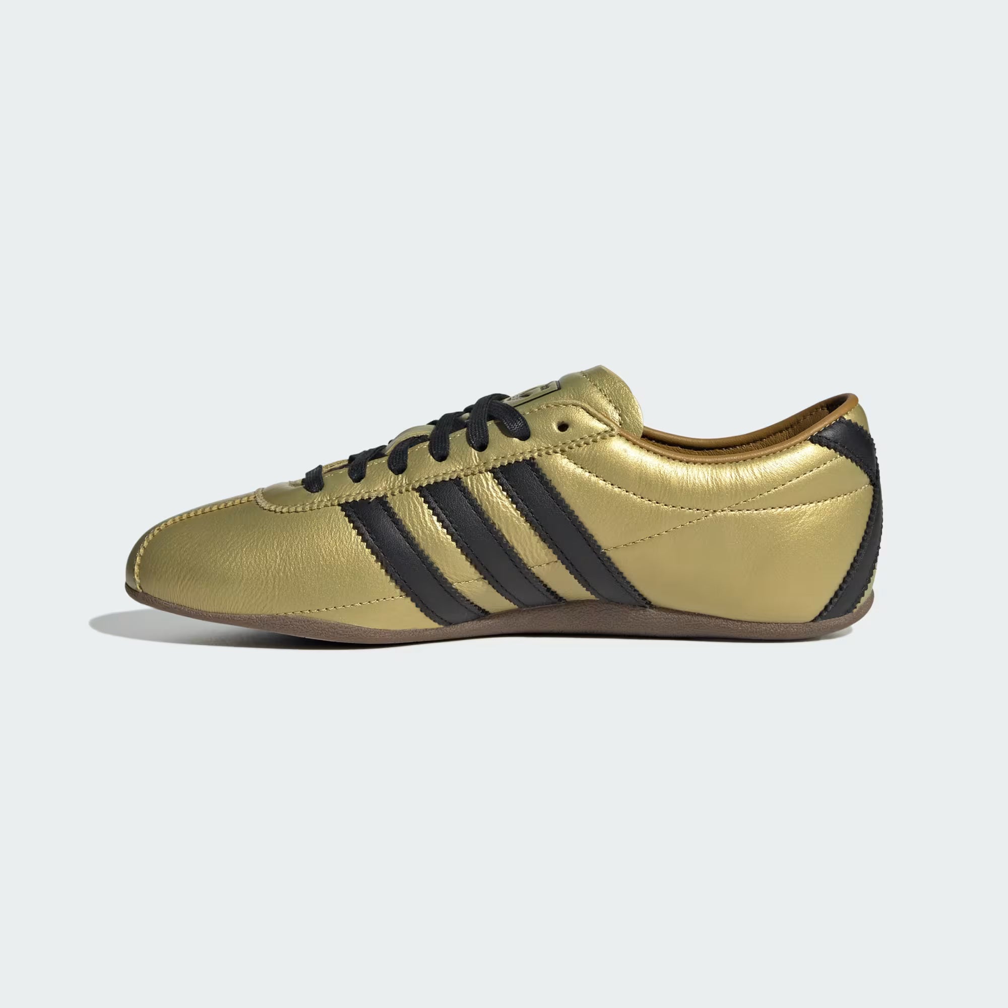 Side angle of womens stylish adidas sneakers on white background showing slim silhouette and gum sole texture