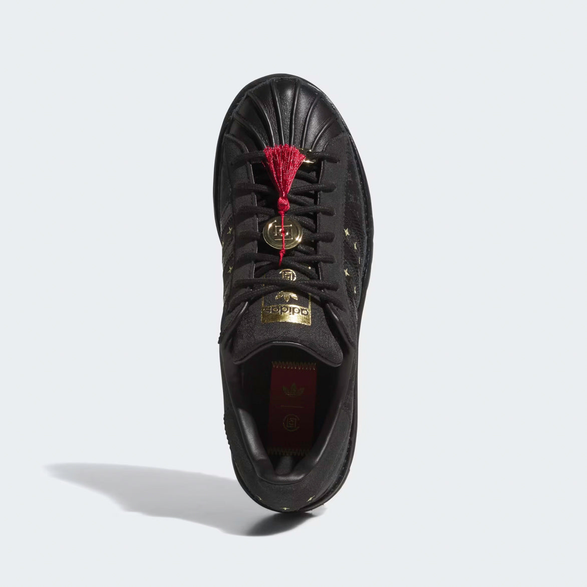 Top-down view of sneaker box, red tassel hangtag, and gold coin tag highlighting CLOT collaboration