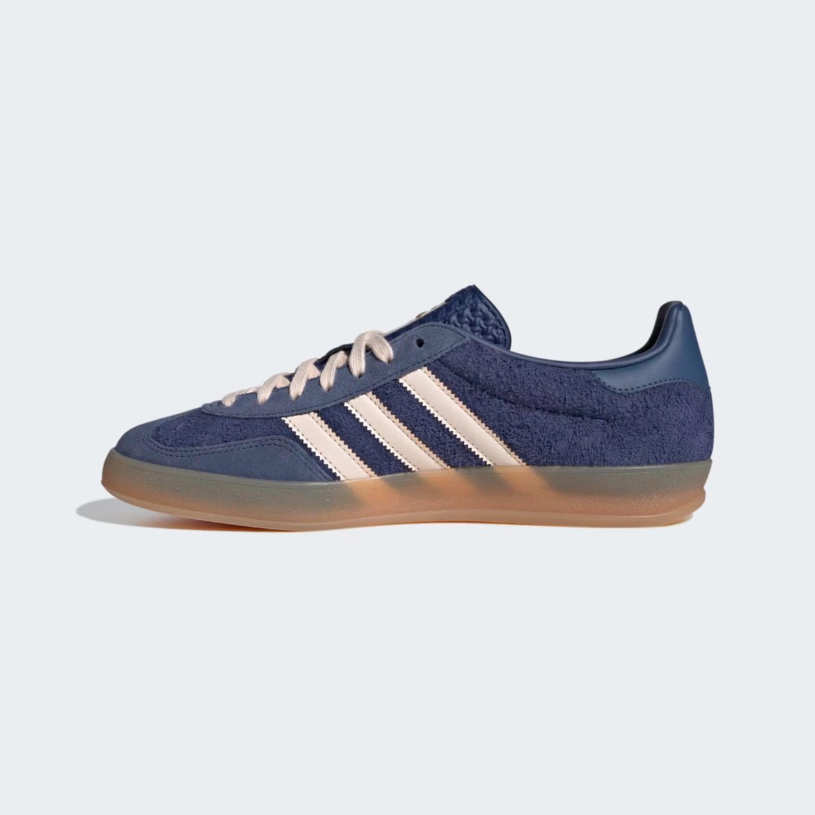 Side view of premium blue sneakers with gum sole, showcasing tonal suede and gold accents.