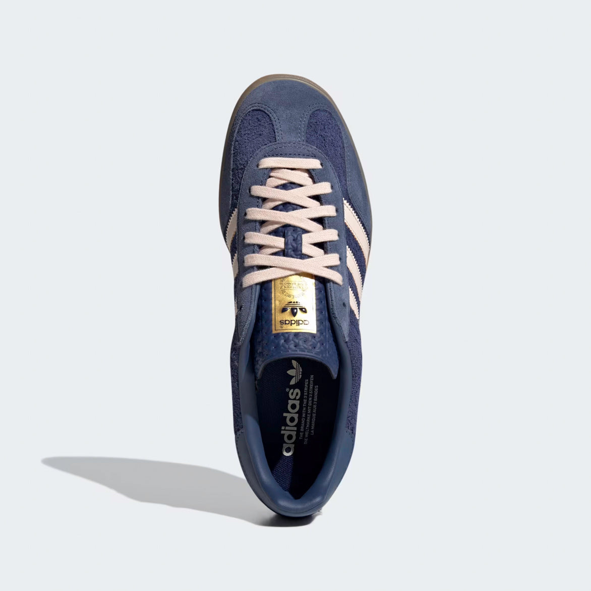 Top view of blue sneakers highlighting the textured tongue and off-white laces.