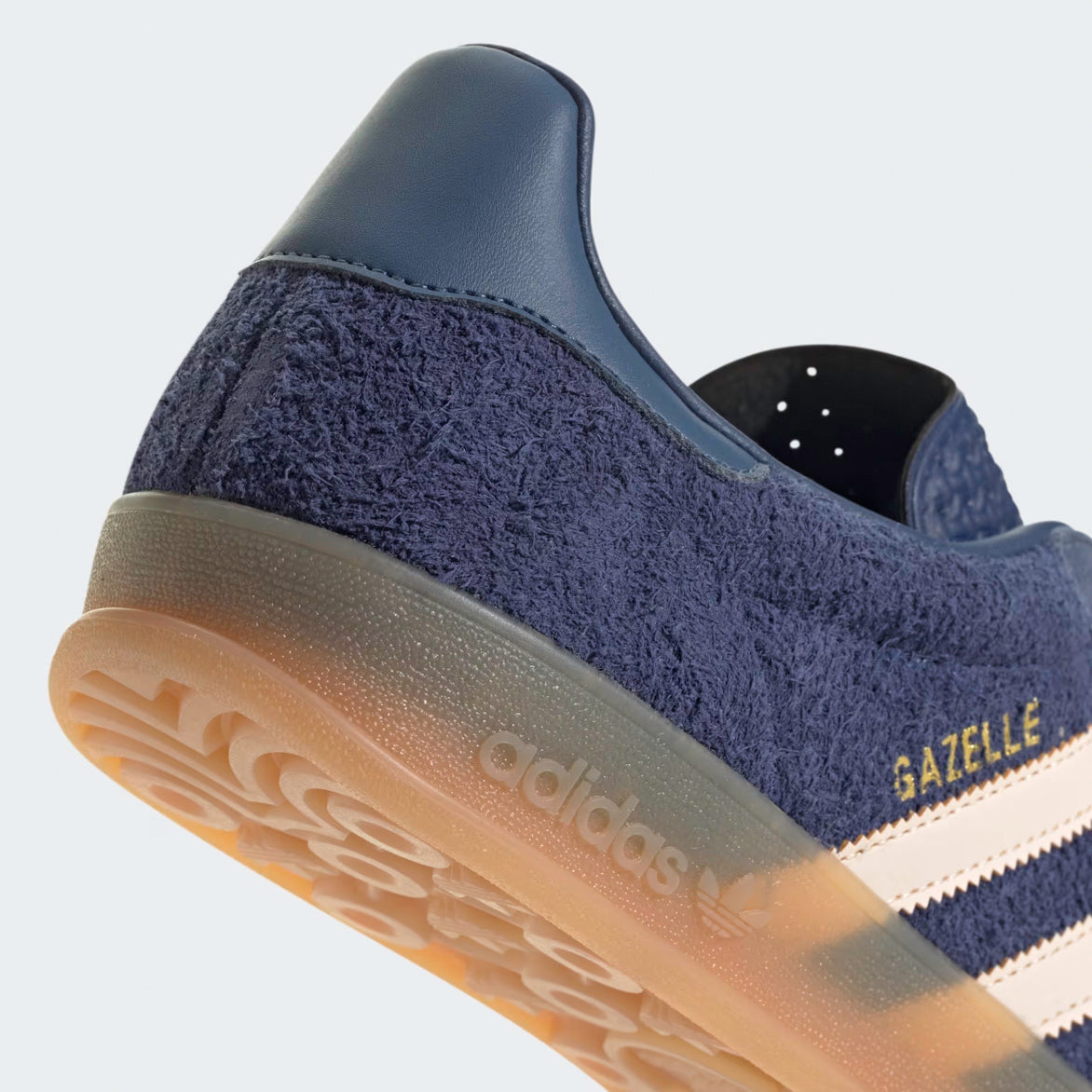 Close-up of the gum sole and Trefoil lug pattern on premium blue sneakers.