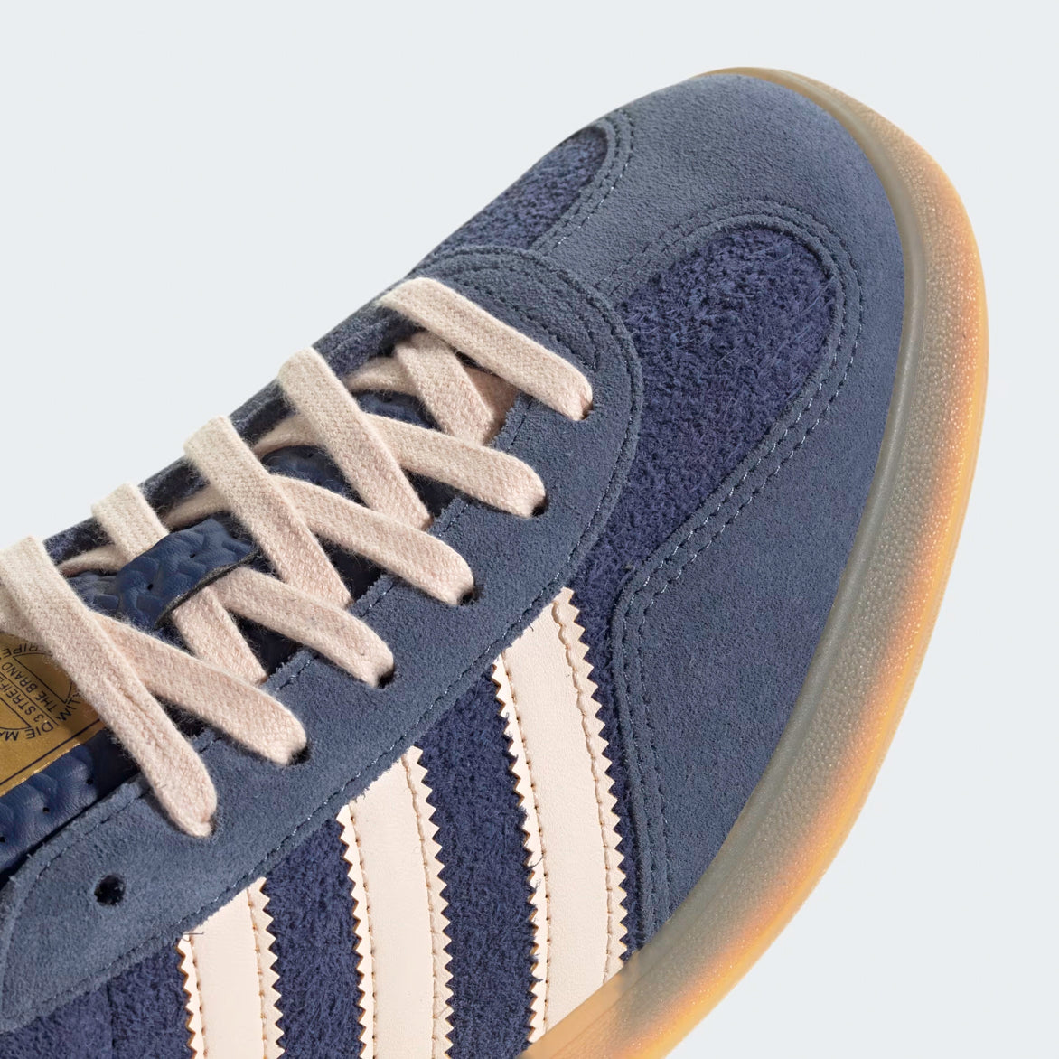 Side view of premium blue sneakers with gum sole, showcasing tonal suede and gold accents.