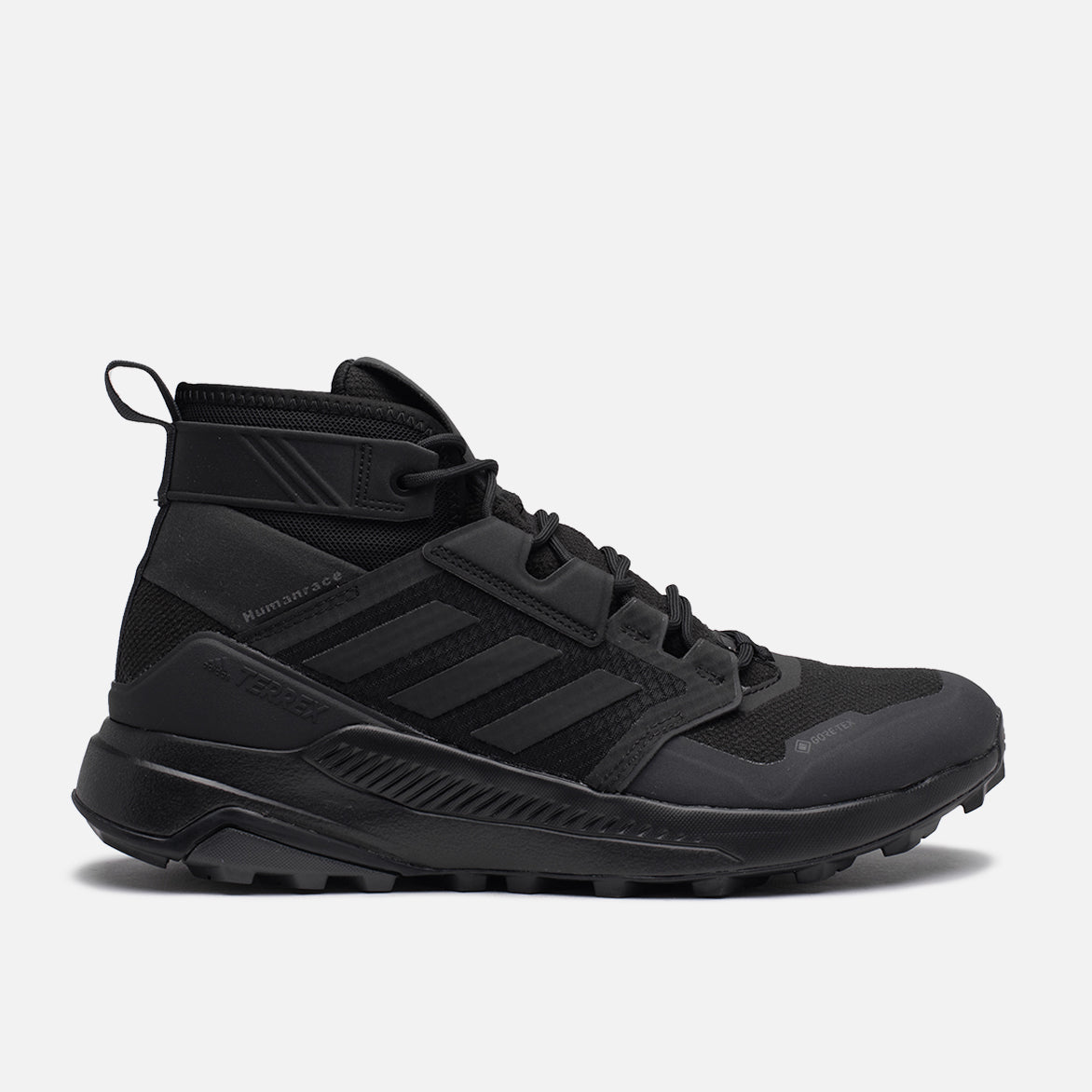 Pharrell x Adidas Terrex Trailmaker Mid Triple Black side view showcasing the deep-lugged Traxion outsole for superior grip.