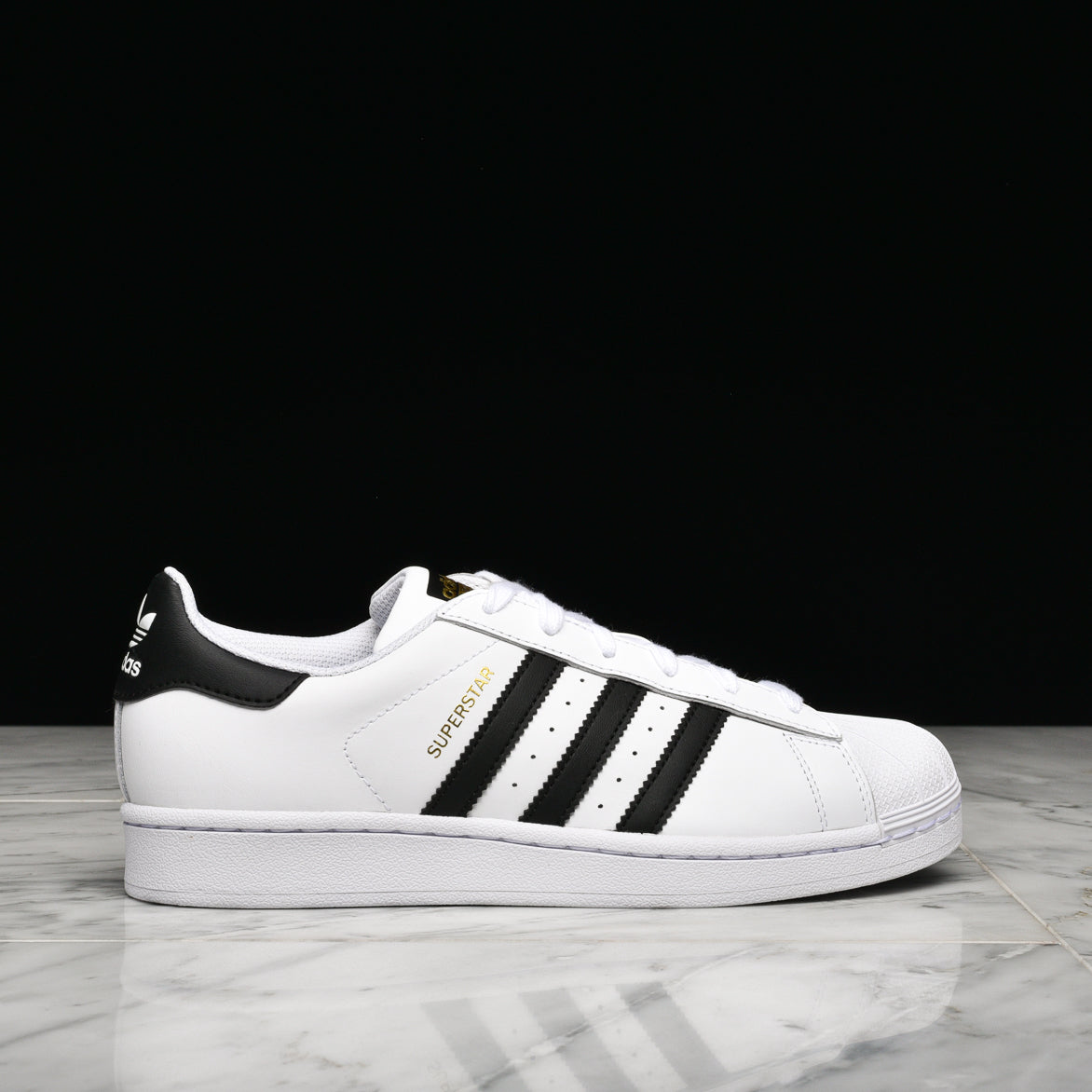 Adidas Superstar GS white and black sneakers showing the full leather upper and rubber shell toe