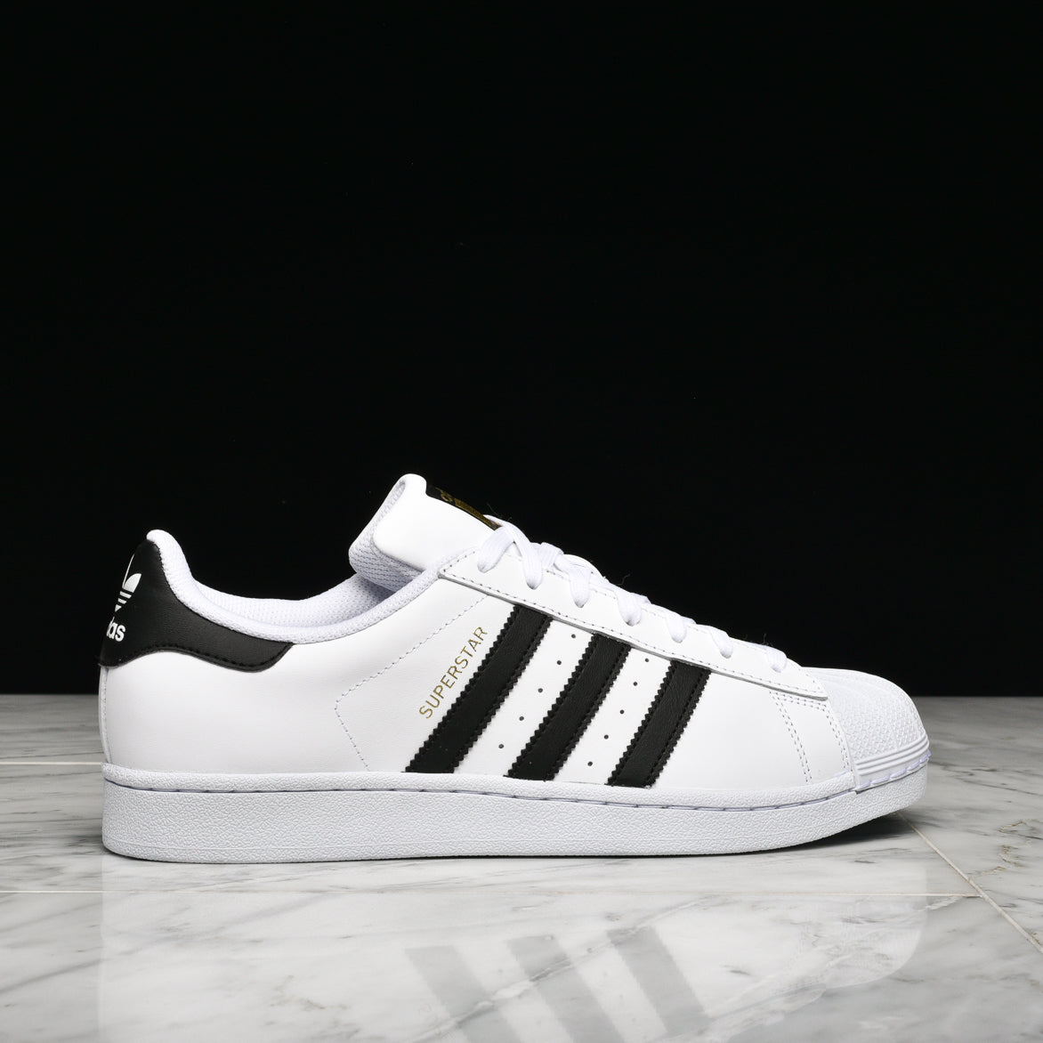 Close-up of adidas superstar shell toe shoes in white and black showing the leather upper and rubber toe cap