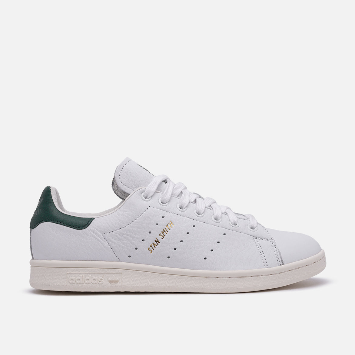 Side view of Stan Smith white green sneakers on a city street.