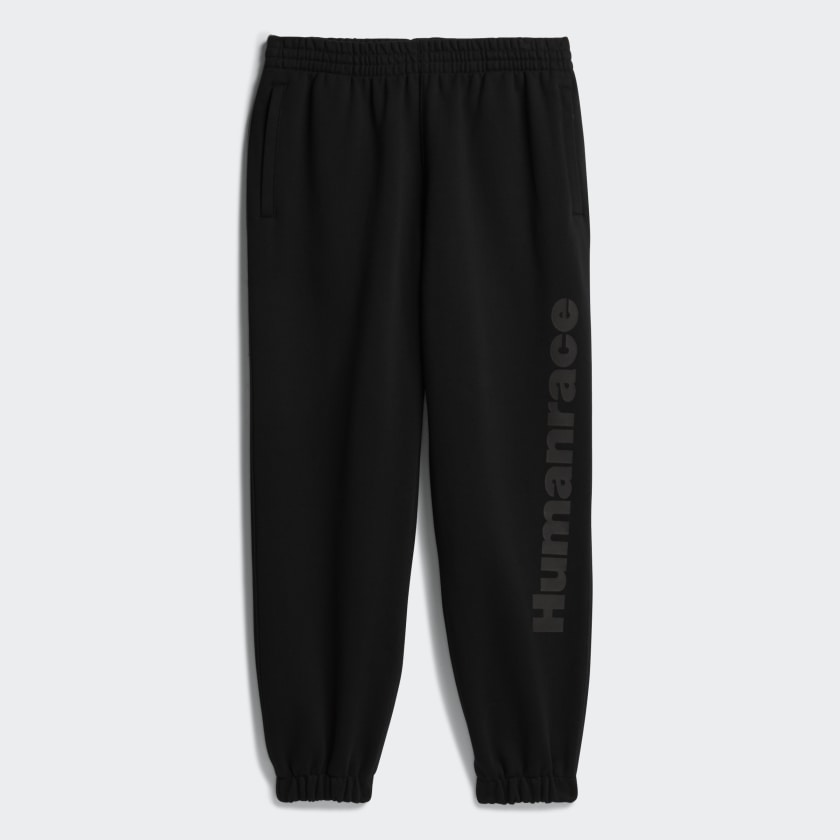 Front view of Pharrell x Adidas black joggers with zippered pockets and elastic cuffs.