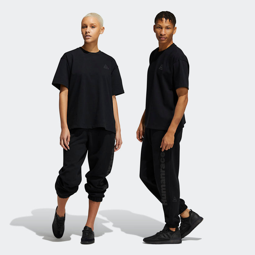 Front view of Pharrell x Adidas black joggers with zippered pockets and elastic cuffs.