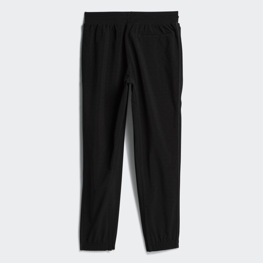 Model wearing all-black Pharrell x adidas track pants with reflective accents for streetwear style
