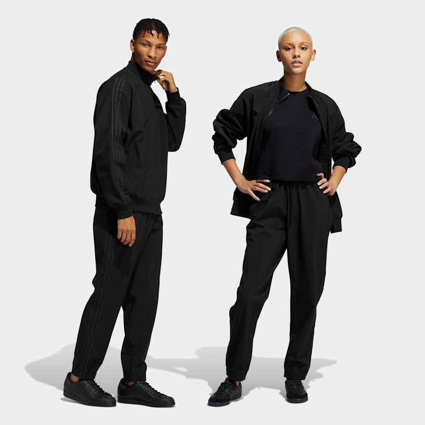 Model wearing all-black Pharrell x adidas track pants with reflective accents for streetwear style